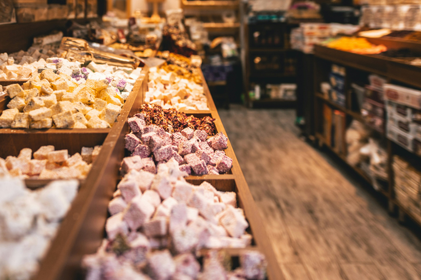 Interior of a general store, with wooden shelves full of candy on one side of the image, and wooden floors and walls for the building