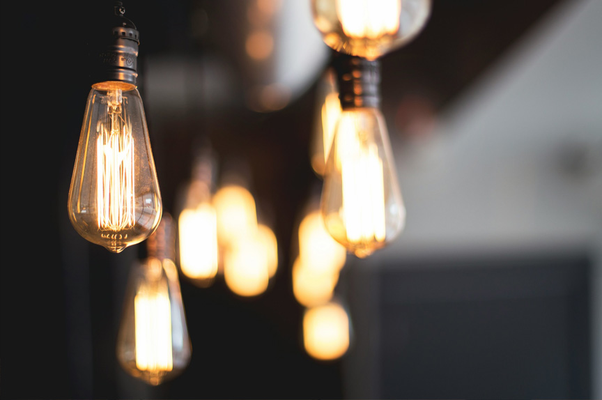 Several teardrop-shaped lightbulbs hanging from the ceiling. More bulbs are in the background, out of focus.